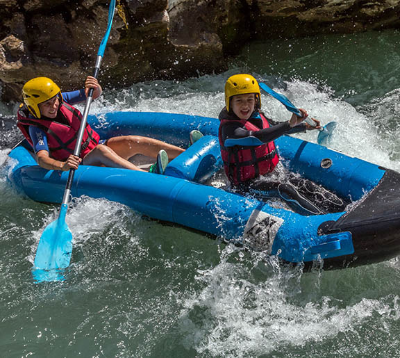 Équipage en canoë-raft bleu franchissant avec enthousiasme un rapide mouvementé dans le verdon avec Planète Rivière.