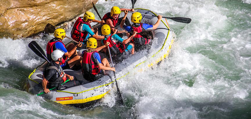 Équipage de rafting en plein effort dans les vagues d'un rapide du Verdon, encadré par Planète Rivière.