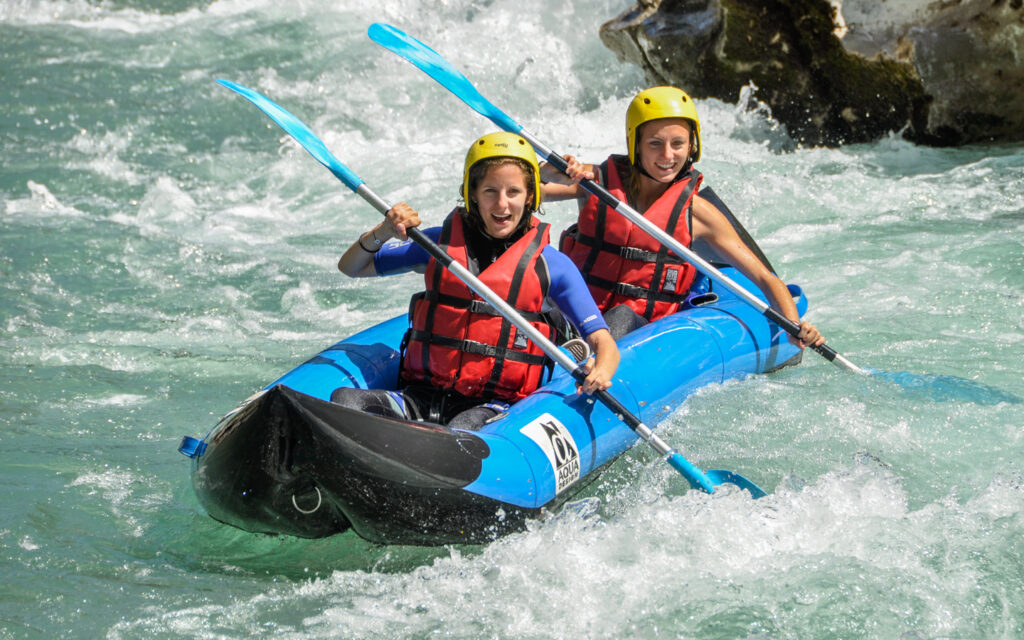 Deux participantes souriantes pagayant en kayak-raft biplace sur une rivière d'eau vive : le Verdon proche Castellane et des Gorges du Verdon