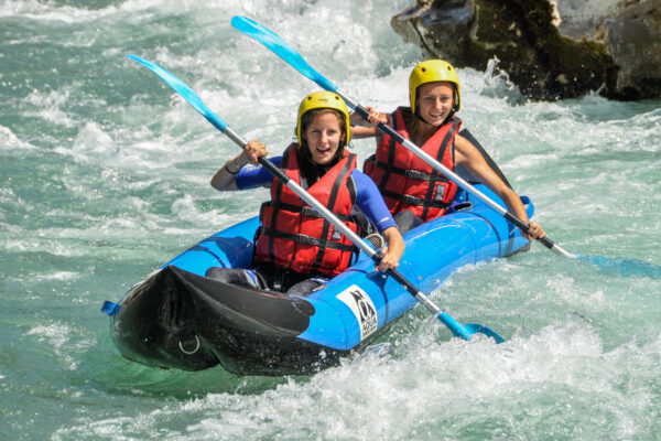 Deux participantes souriantes pagayant en kayak-raft biplace sur une rivière d'eau vive : le Verdon proche Castellane et des Gorges du Verdon