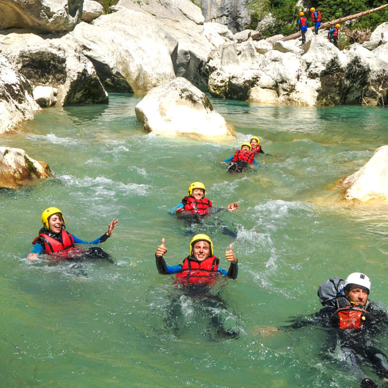 Aventuriers souriants faisant du "floating" dans les eaux claires d'un canyon rocheux.